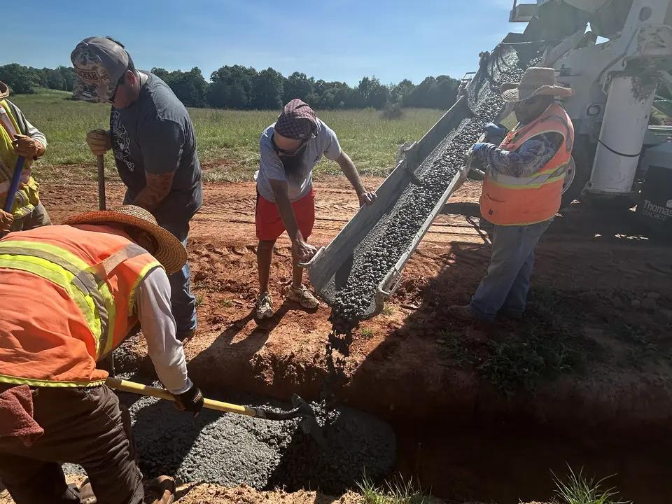 Crew backfilling an open utility trench with flowable fill from a mixer truck on a Greenville County, SC site