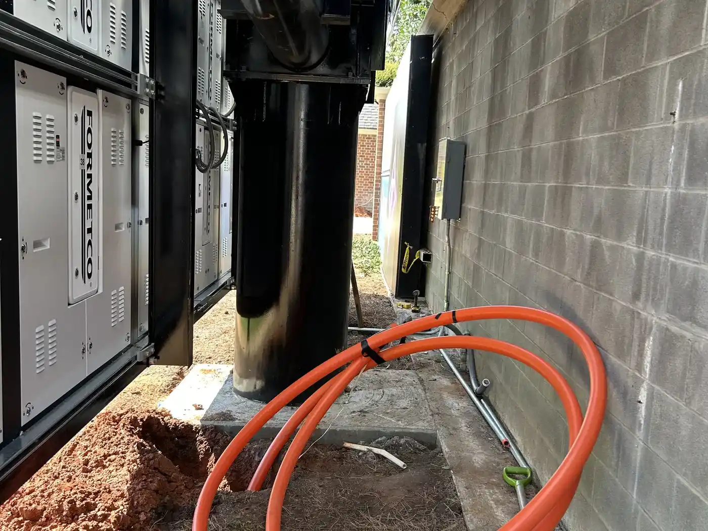 Orange HDPE conduit bored up to an electrical service enclosure on a commercial building in Travelers Rest, SC