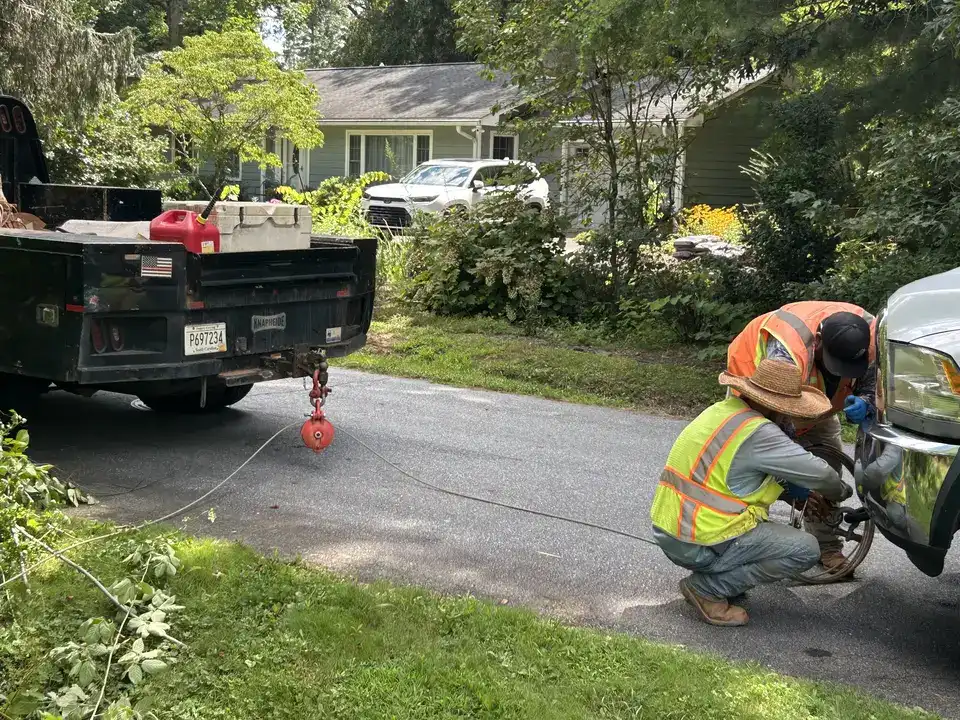 Crew rigging the pullback line across a residential driveway in Hendersonville, NC with no cut through the pavement