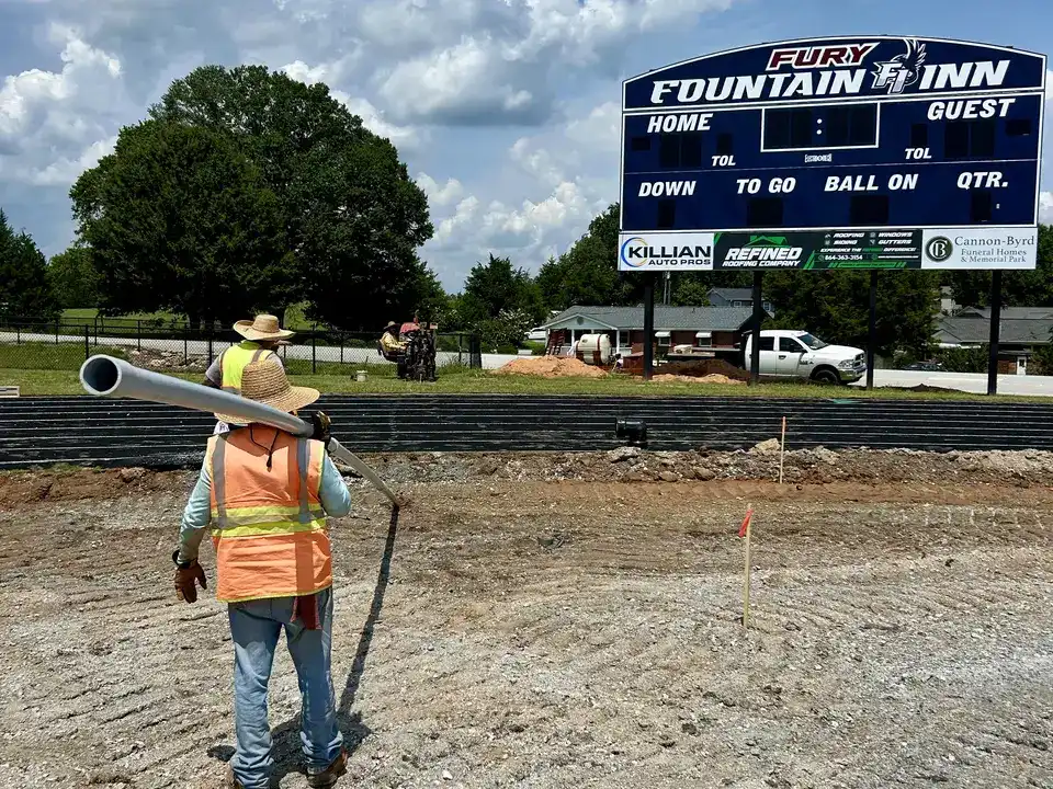 Carrying pipe across the Fountain Inn, SC athletic field during a commercial underground utility installation